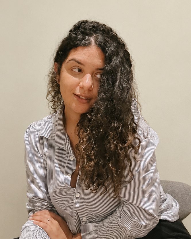 Retrato de Letícia Lupette de camisa listrada, olhando de lado